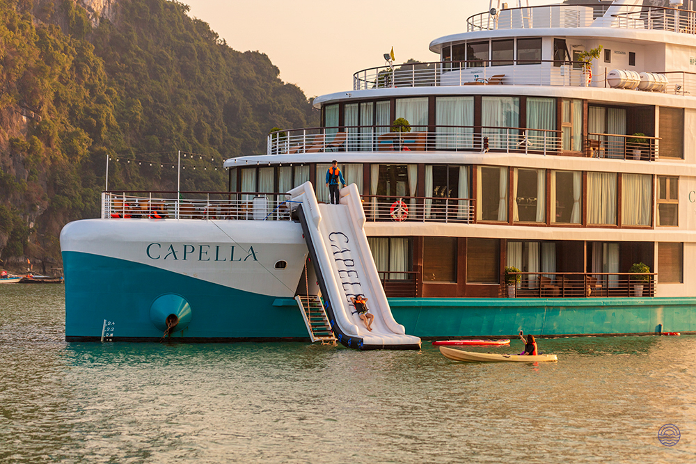 Guests enjoy a thrilling water slide from the Capella cruise ship in scenic Halong Bay.