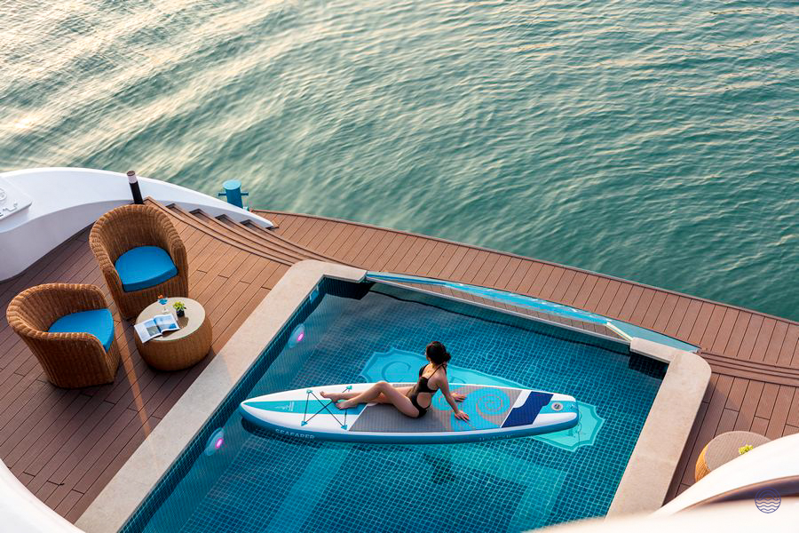 Woman relaxing on a paddleboard in a pool on a luxury cruise ship in Halong Bay.