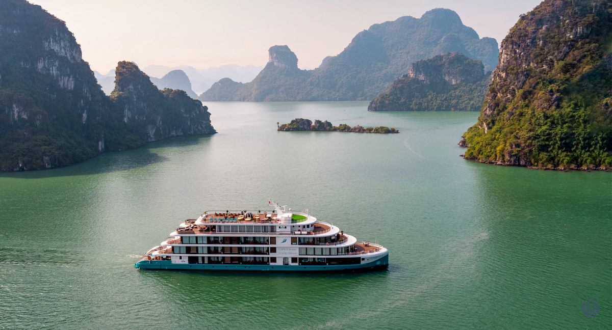 The Capella Cruise ship navigates the emerald waters surrounded by majestic islands in Halong Bay.