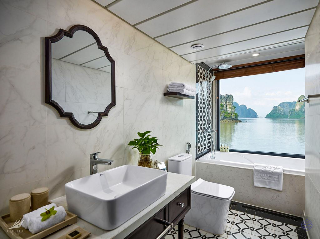 A luxurious cruise bathroom with an ocean-view bathtub overlooking the stunning limestone karsts of Halong Bay.