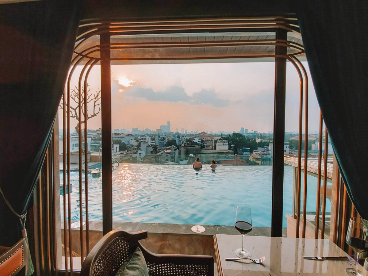 A couple enjoys a romantic sunset in a rooftop infinity pool overlooking Hanoi.