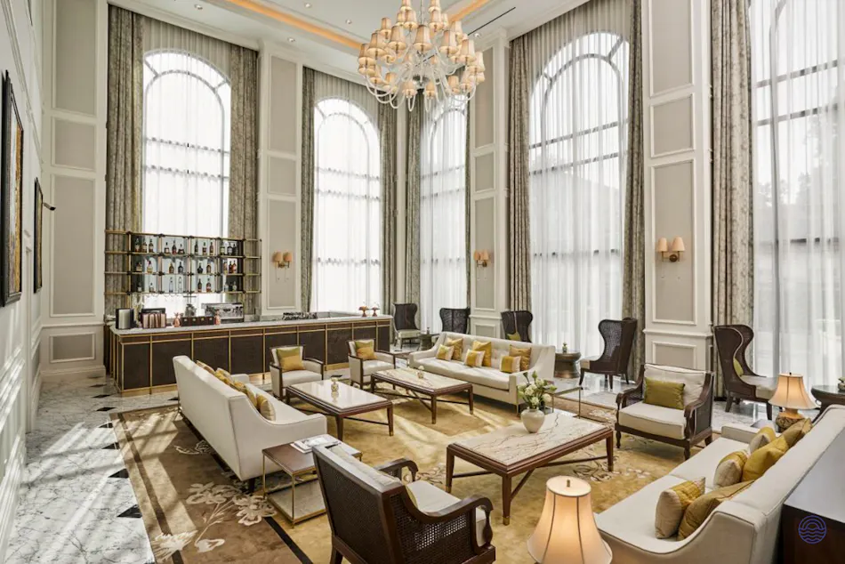 A luxurious hotel lounge in Ho Chi Minh with high ceilings, arched windows, and elegant chandeliers.