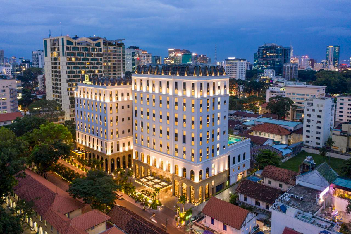 The elegant Mai House Saigon Hotel stands illuminated at dusk in bustling Ho Chi Minh City.