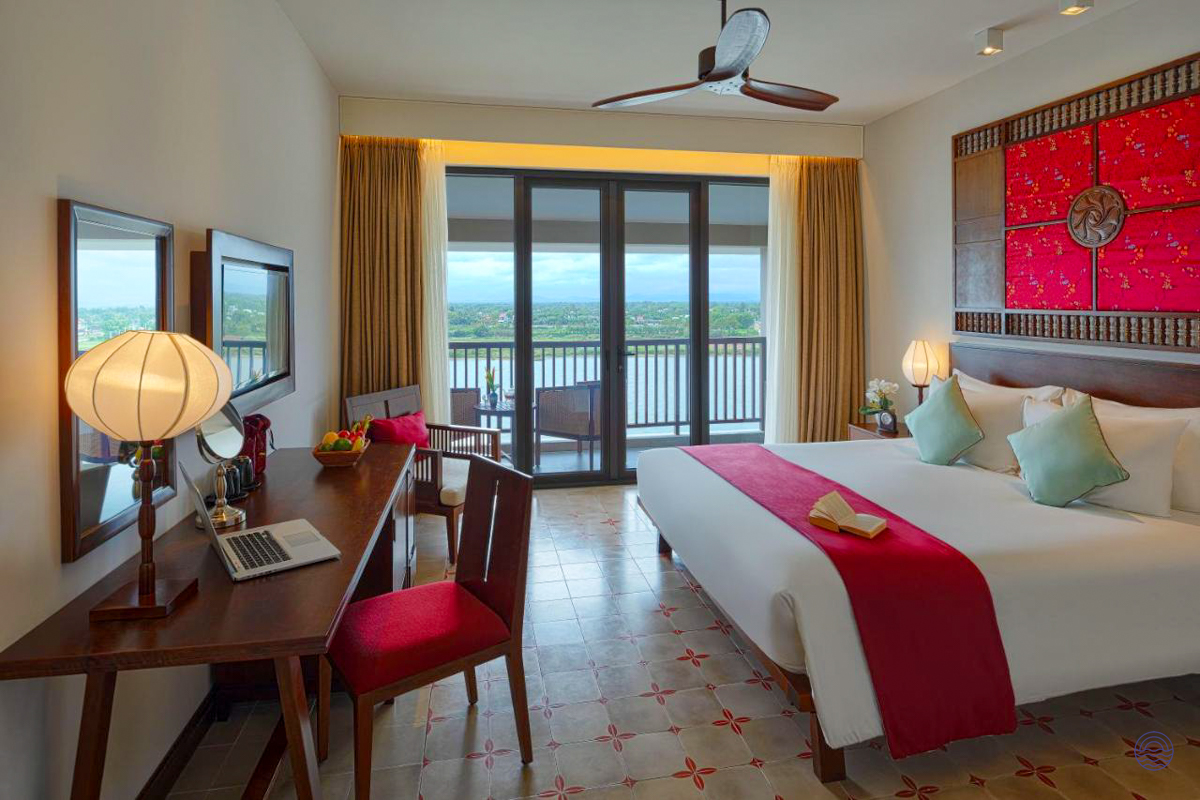 Relax in this charming Hoi An hotel room with a comfortable bed and scenic river balcony.