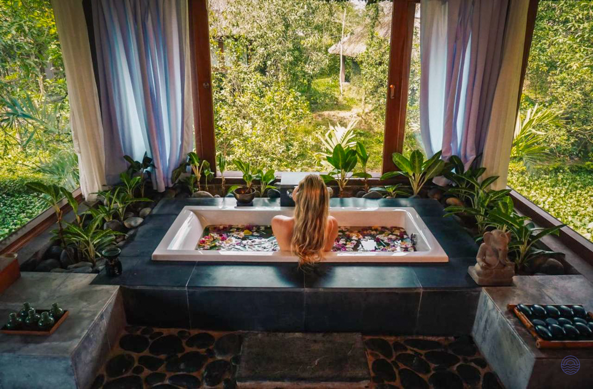 A woman enjoys a relaxing flower bath overlooking the lush tropical gardens at Pilgrimage Village Resort in Hue.
