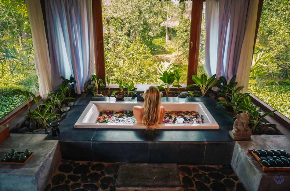 A woman relaxes in a luxurious flower-filled bathtub overlooking a lush jungle in Vietnam.