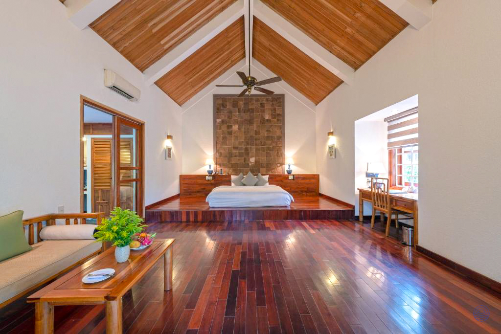 Spacious, luxurious Honeymoon Pool Hut in Hue, featuring a large bed and elegant wooden decor.
