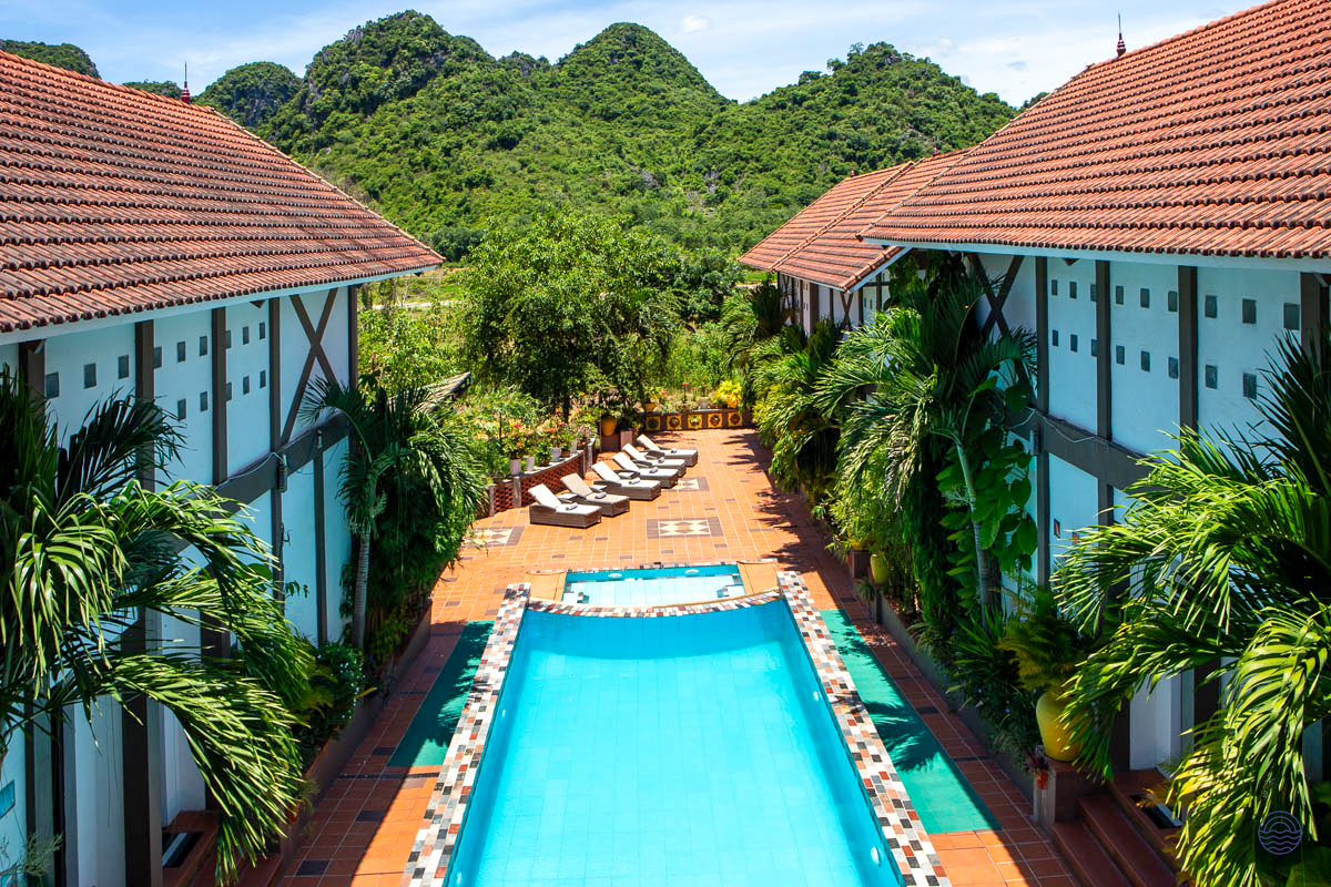 A tranquil swimming pool and lounge chairs at Victory Villas in Phong Nha, with green mountains.