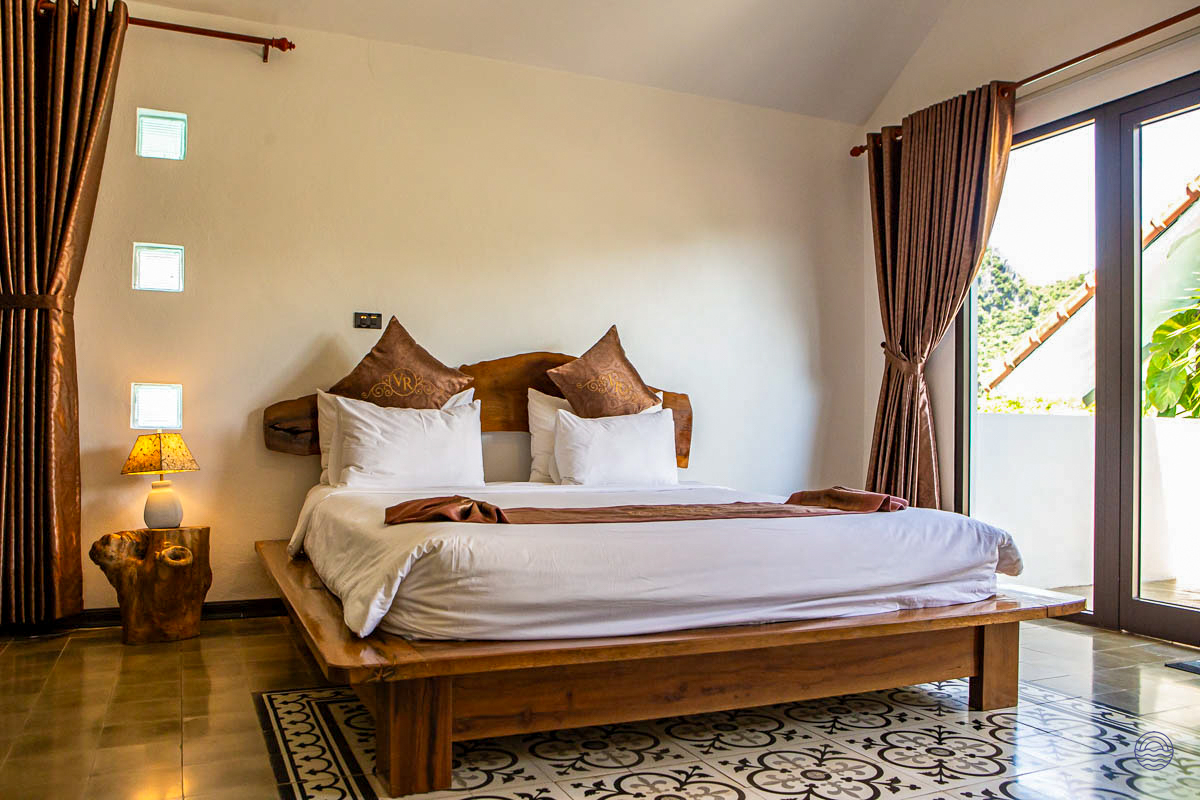 A serene bedroom at Victory Road Villas, Phong Nha, offering a comfortable bed and private balcony views.