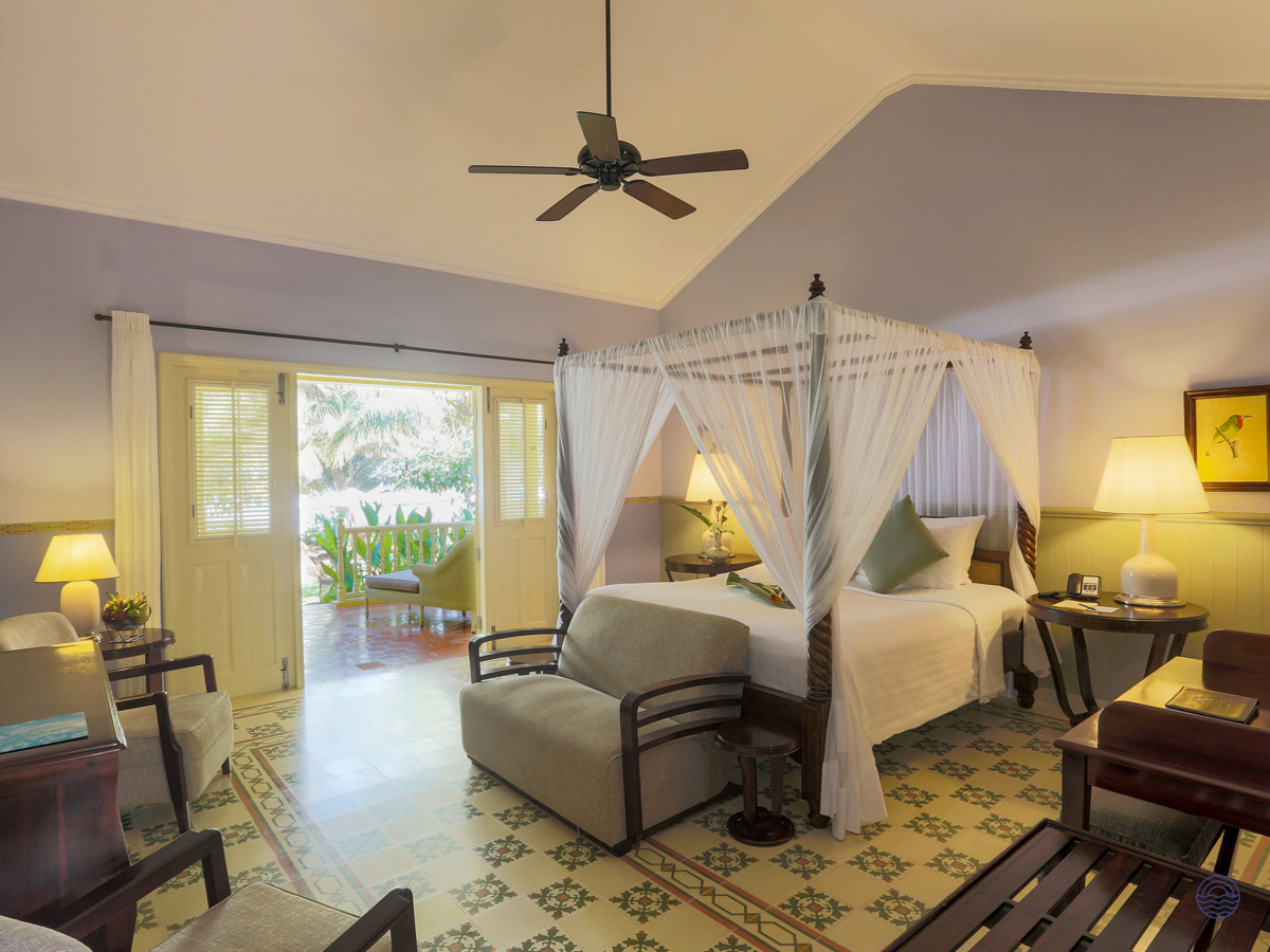 Spacious Phu Quoc resort room with a draped four-poster bed and doors opening to a garden.
