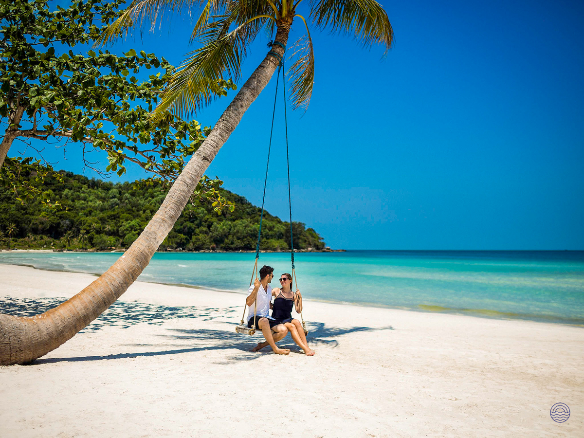 Smiling couple enjoying a swing on a beautiful white sand beach in Phu Quoc.