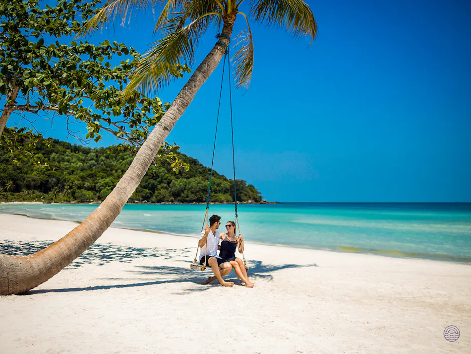 Smiling couple enjoying a swing on a beautiful white sand beach in Phu Quoc.