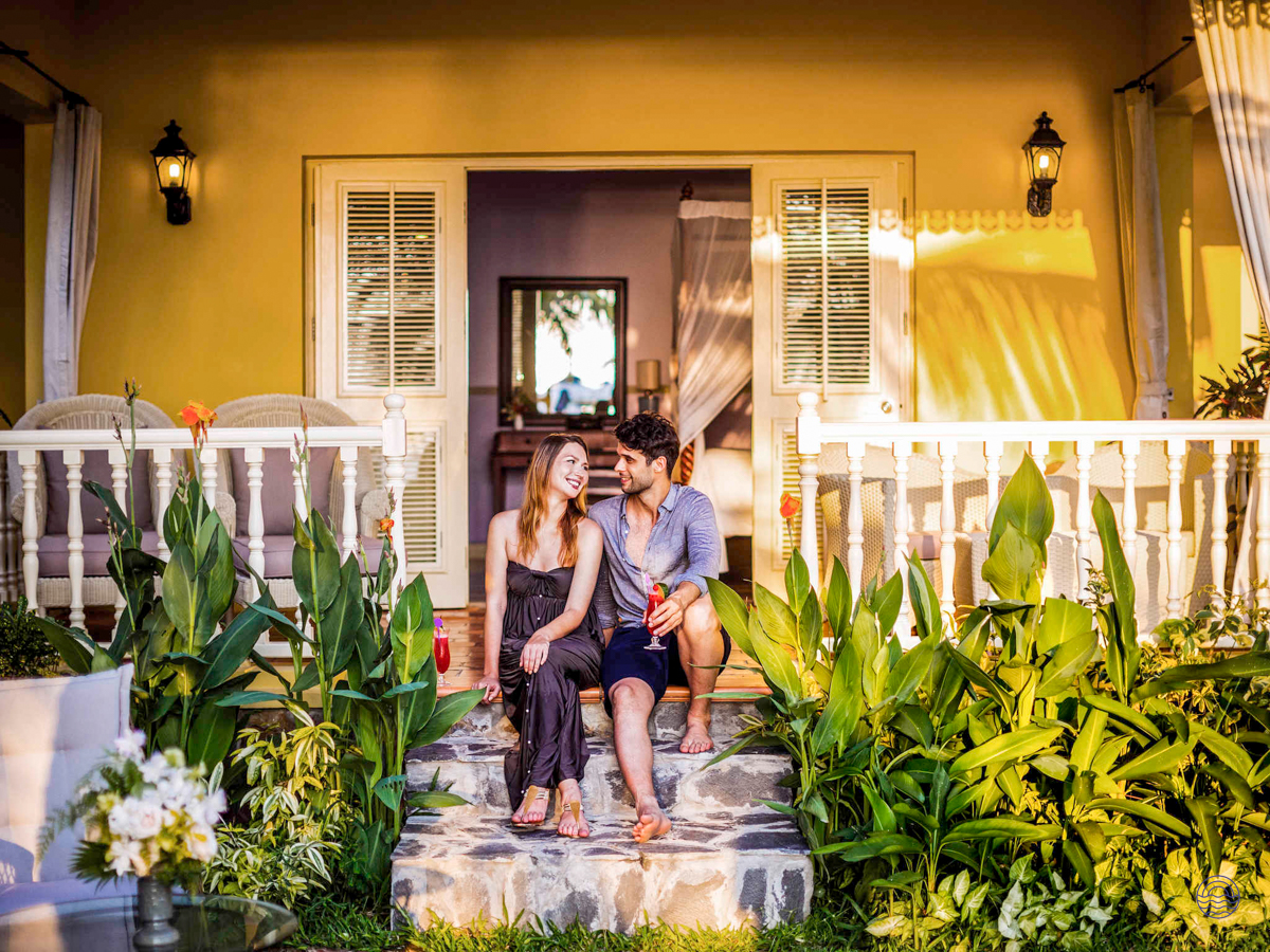 A happy couple relaxing on the steps of a beautiful yellow villa in Phu Quoc.