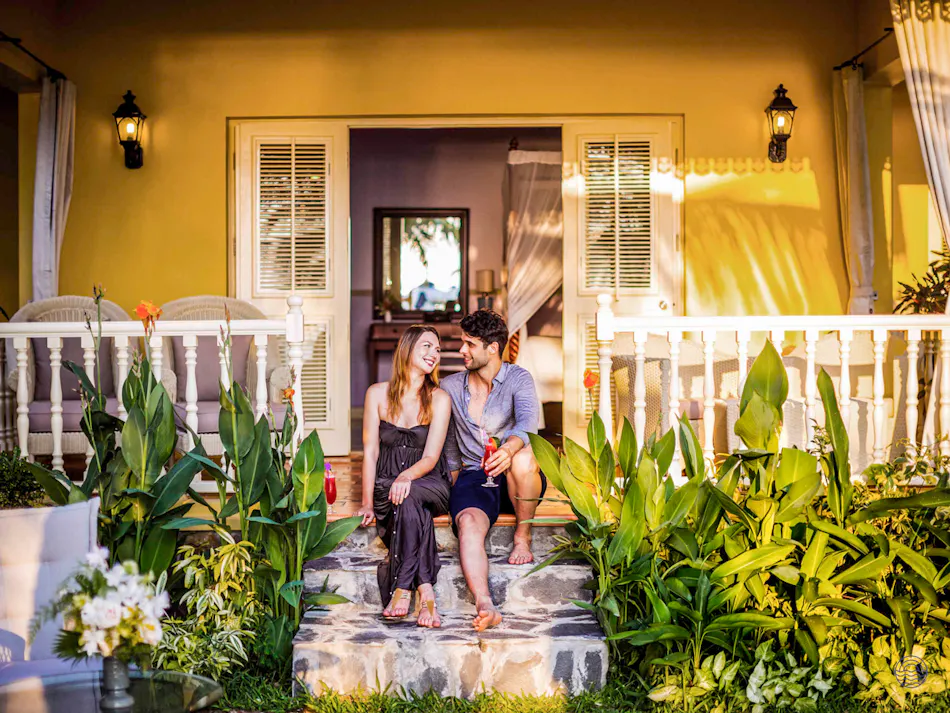 A happy couple relaxing on the steps of a beautiful yellow villa in Phu Quoc.