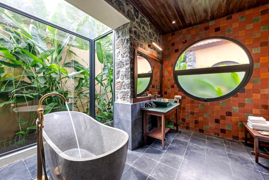 Relax in this tranquil bathroom at Tam Coc Retreat, featuring a stone tub and garden views.