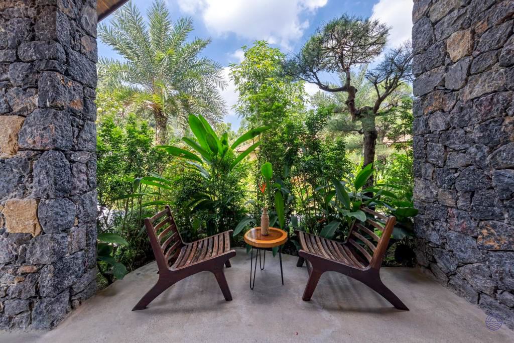 Peaceful outdoor patio with two chairs and a table, surrounded by lush tropical gardens in Tam Coc.