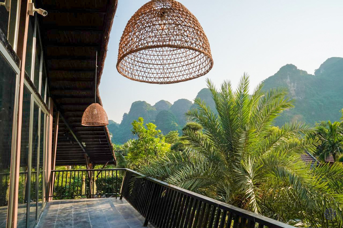 A scenic balcony view at Tam Coc Retreat, overlooking lush tropical gardens and dramatic limestone karsts.