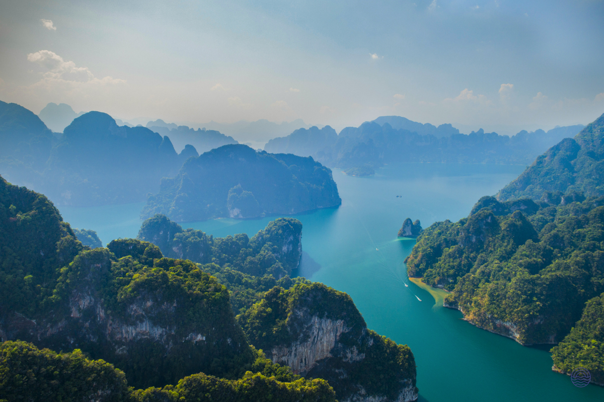 Majestic limestone karsts covered in green foliage rise from the emerald waters of Halong Bay, Vietnam.