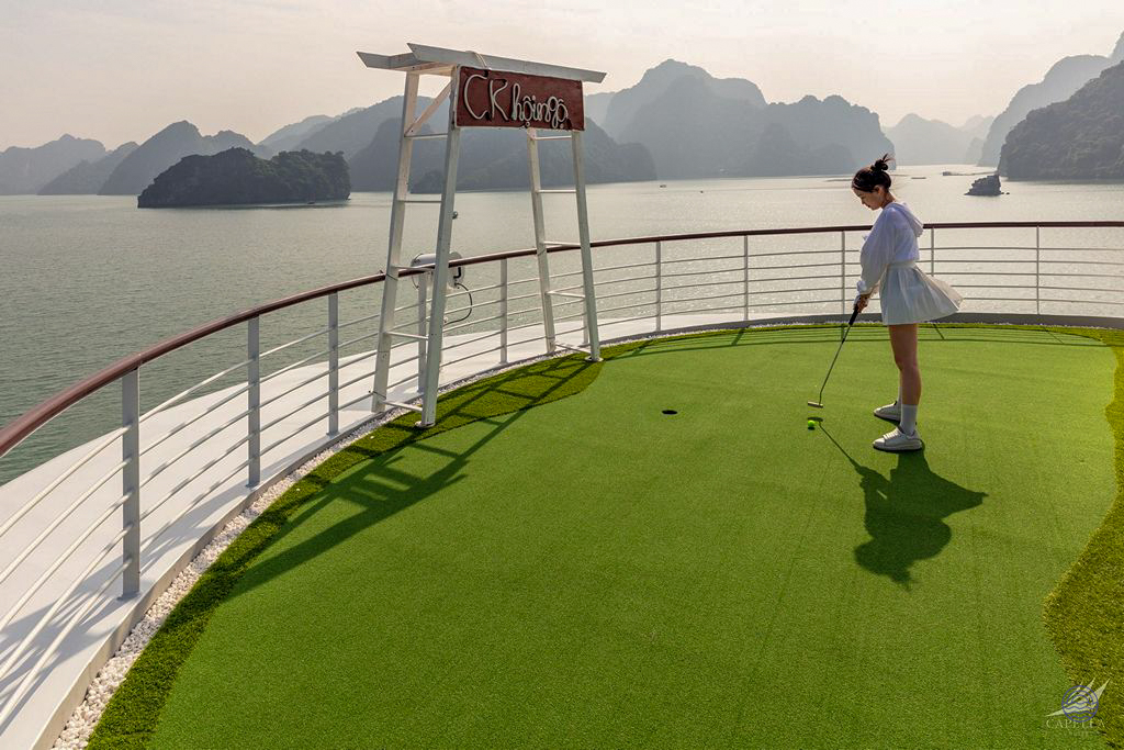 A woman putts on the mini-golf course aboard a cruise ship in beautiful Halong Bay.