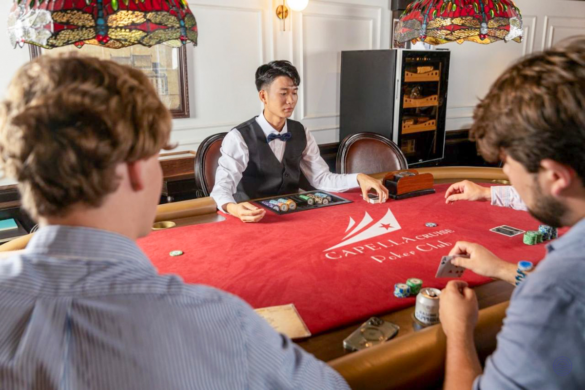 Guests enjoy a focused game of poker with a dealer in a cruise ship's elegant club.