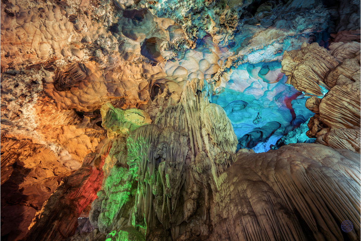 Colorful lights illuminate the intricate rock formations inside a captivating cave in Tam Coc, Vietnam.