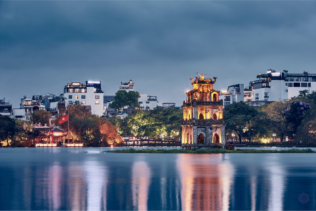 The iconic Turtle Tower glows beautifully on Hoan Kiem Lake in Hanoi at dusk.