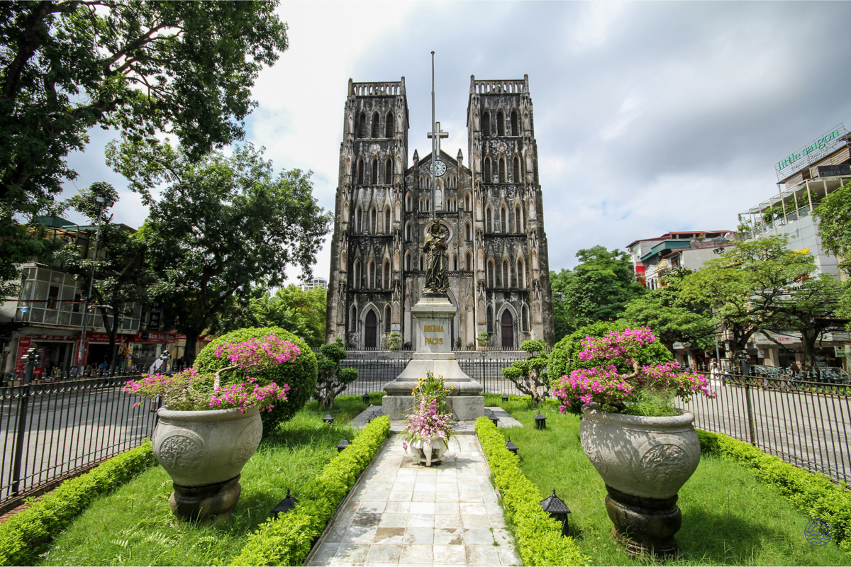 St. Joseph Cathedral in Hanoi stands majestically, surrounded by lush green gardens and blooming flowers.
