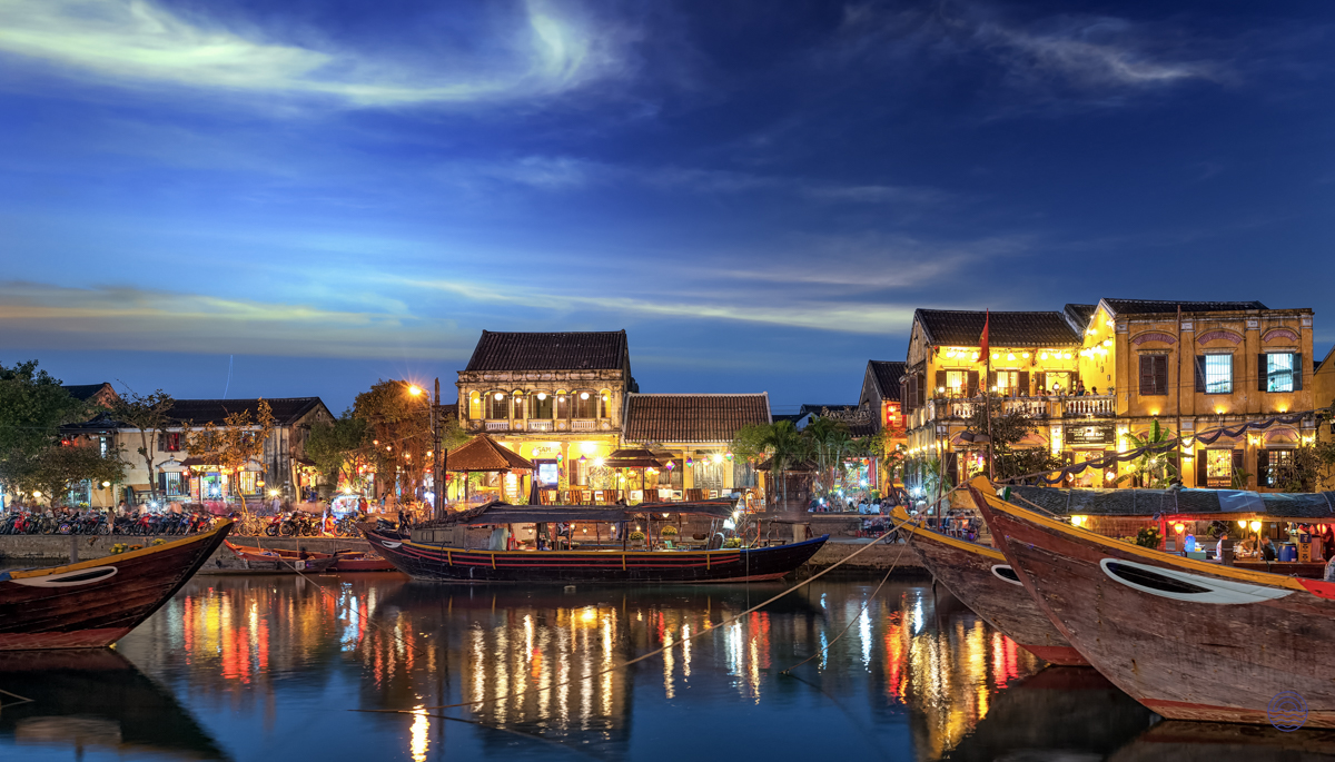 Hoi An Ancient Town glows at night, with traditional boats reflecting warm lights on the river.
