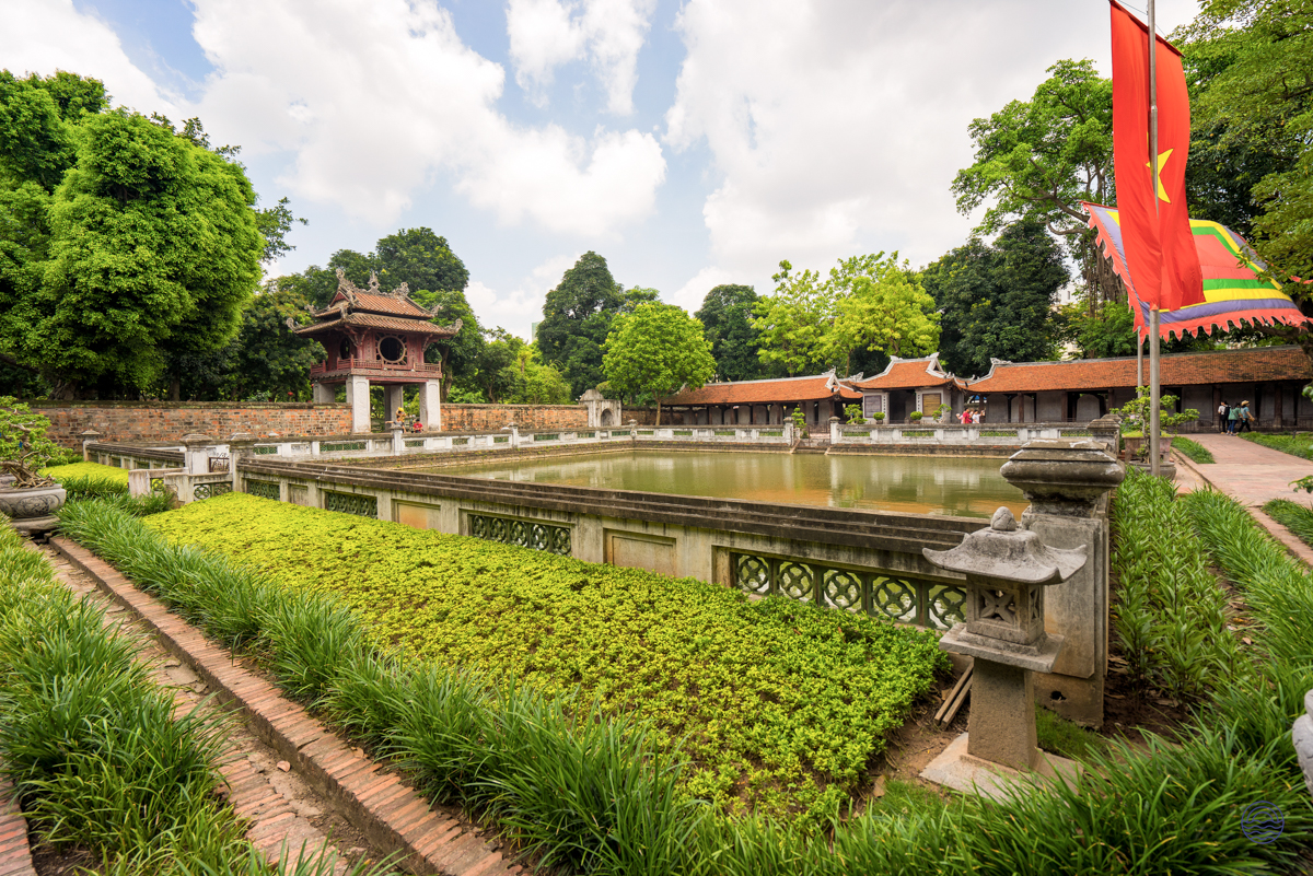 Beautiful traditional Vietnamese architecture surrounds a tranquil pond and green gardens in historic Hue.