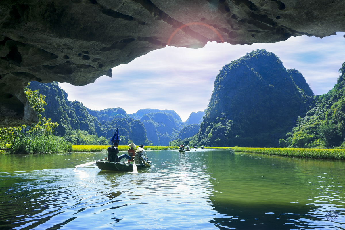 A serene sampan boat ride through the scenic waterways of Tam Coc, surrounded by lush karsts.