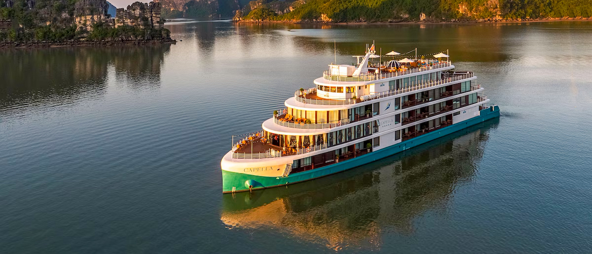 A luxurious cruise ship sails calmly through the iconic limestone karsts of Halong Bay.