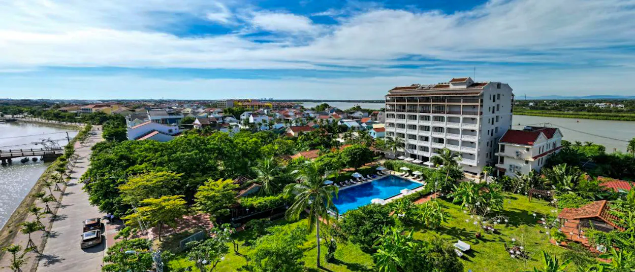 Peaceful RiverTown Hoi An Resort & Spa, with a blue swimming pool and lush gardens by the river.