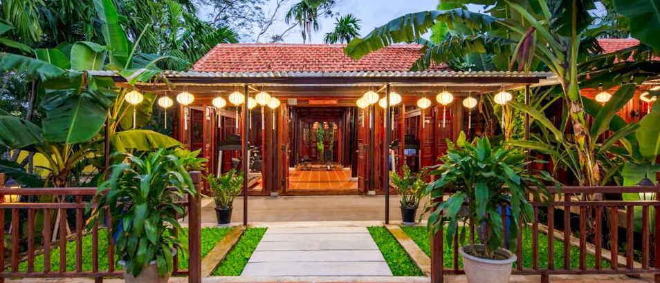 An inviting resort entrance in Hoi An, Vietnam, with glowing lanterns and lush tropical plants.