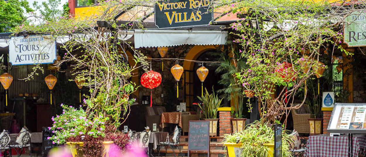 Lush greenery and colorful lanterns adorn the welcoming entrance of Victory Road Villas in Phong Nha.