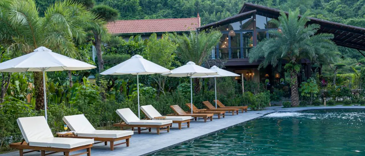 Serene swimming pool with lounge chairs and umbrellas at a beautiful Tam Coc retreat in Vietnam.