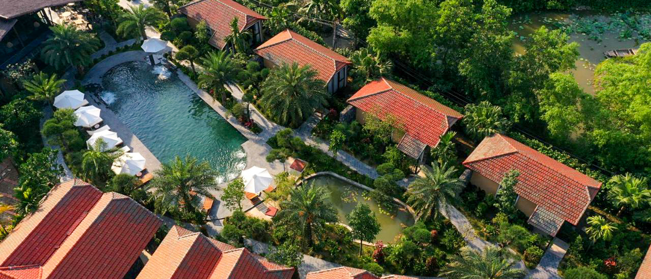 Aerial view of Tam Coc Retreat featuring red-roofed bungalows, a swimming pool, and lush tropical gardens.