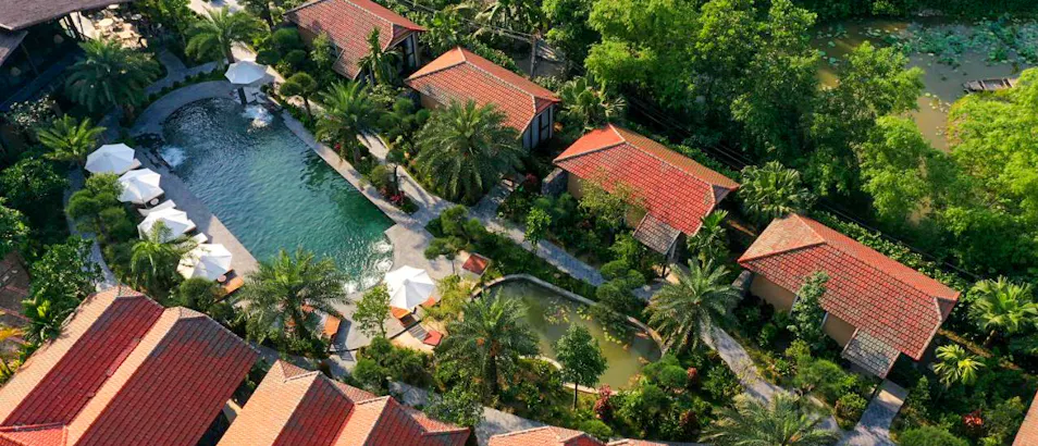 Aerial view of Tam Coc Retreat featuring red-roofed bungalows, a swimming pool, and lush tropical gardens.