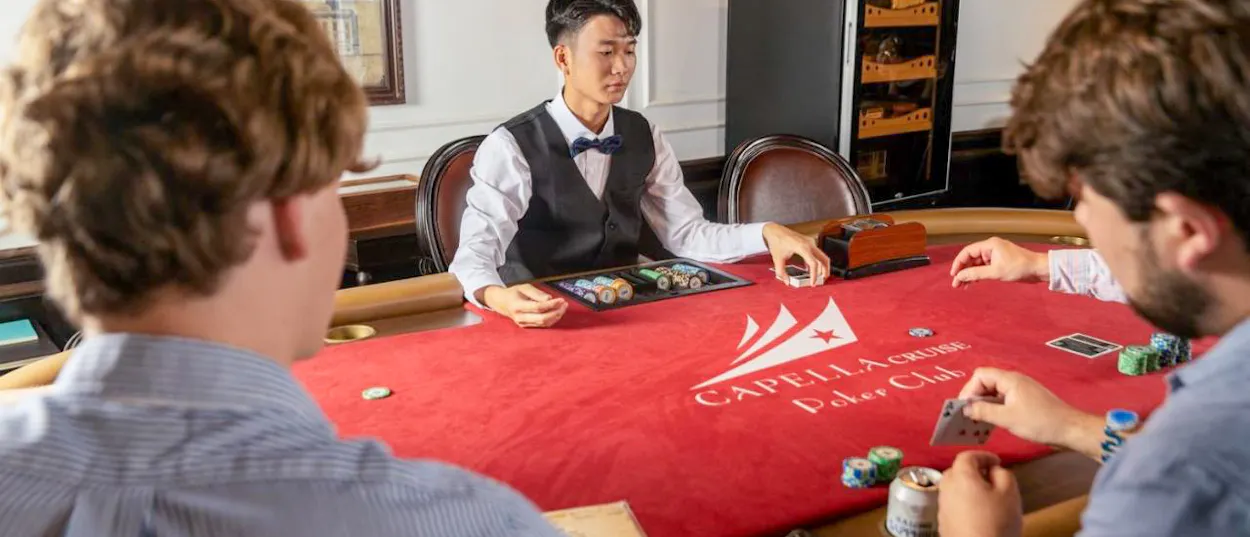 Guests enjoying a game of poker with a dealer on a Capella Cruise in Halong Bay.