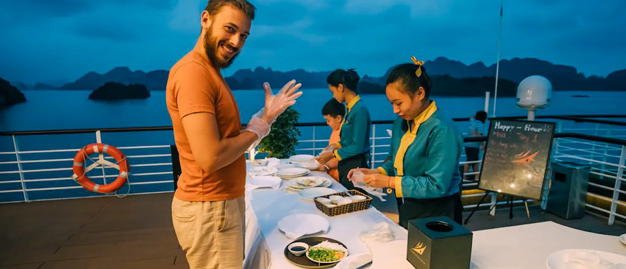 A smiling man puts on gloves for a cooking class on a cruise ship in Halong Bay.