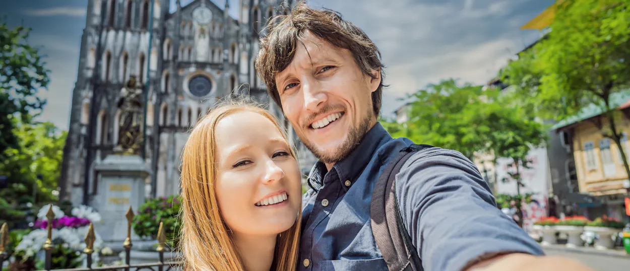 A happy couple smiles for a selfie in front of St. Joseph Cathedral in Hanoi.