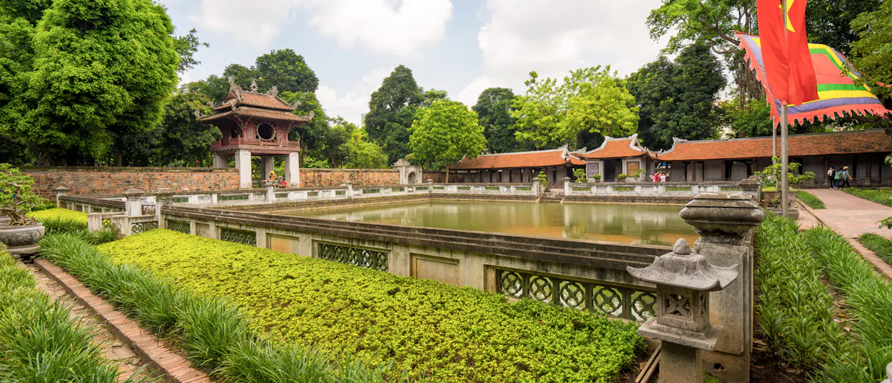 Historic Vietnamese temple complex in Hue featuring traditional buildings, a large pond, and lush greenery.