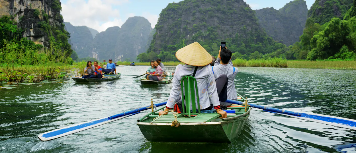Tourists enjoy a serene sampan boat ride through the scenic waterways of Tam Coc, Vietnam.